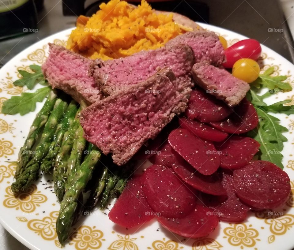 Beef tenderloin with sweet potato, roasted asparagus, sliced beets, tomatoes, and arugula.
