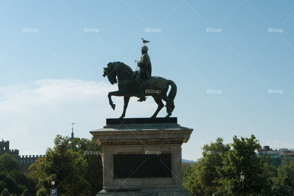A statue in the park of the Citadel in Barcelona. On the head of the sculpture there is a seagull.