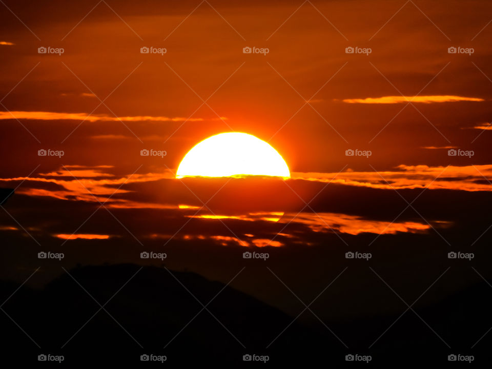 Sunset or dusk wallpaper - This photograph captured in India shows sun goes down behind the mountains and clouds at the time of sunset looking beautiful.