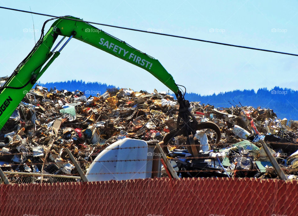 Giant industrial claw digging through scrap metal at a wrecking yard