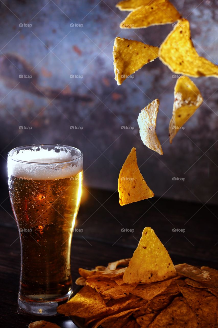 Glass of cold beer and flying chips