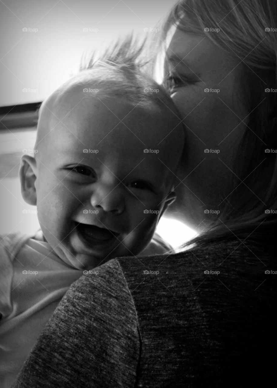 Beautiful baby boy's smile while mom holds him