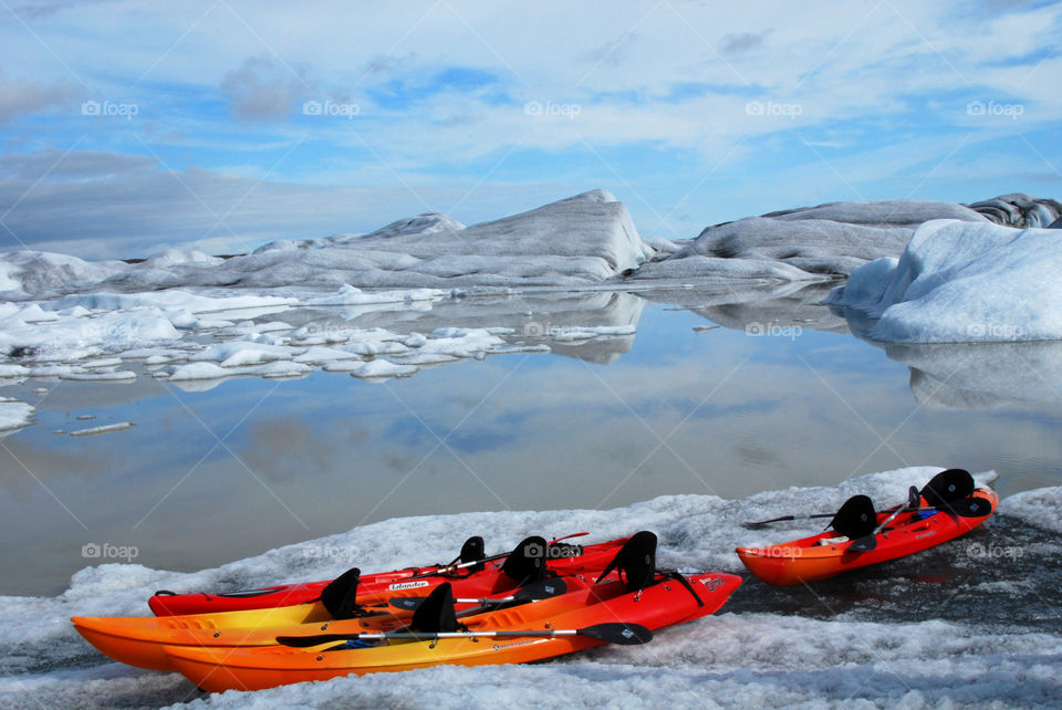 Bright red kayaks resting against the cool landscape of a glacial outlet in Iceland.