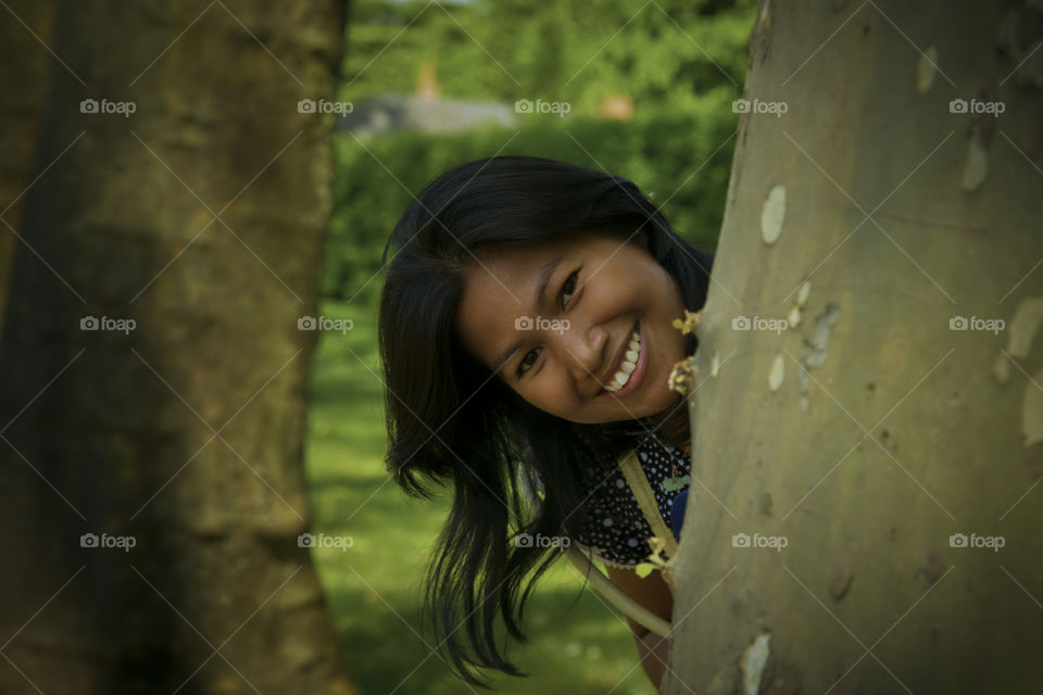 Spring arrived and it's time for hide and seek fun. Asian woman hiding behind tree