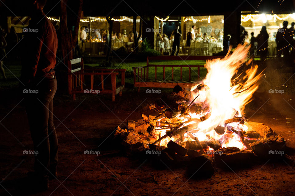 Image at night with big fire and people enjoying a function in the background