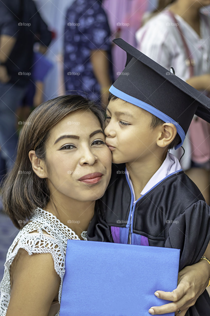 .Portrait son graduated from kindergarten kissing mother