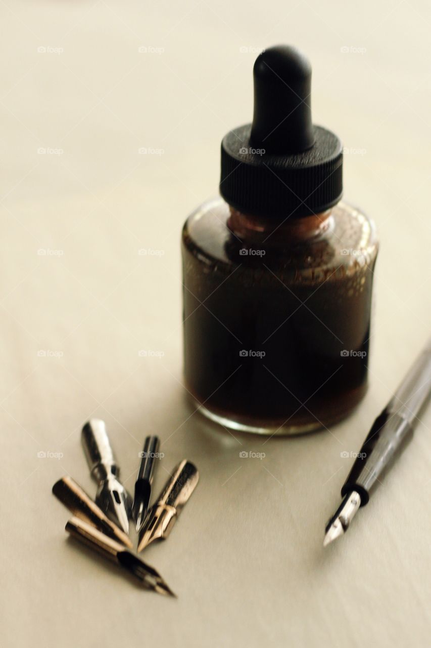 Arts & Crafts Supply - sepia ink bottle with various-sized metal nibs, nib in holder on parchment paper