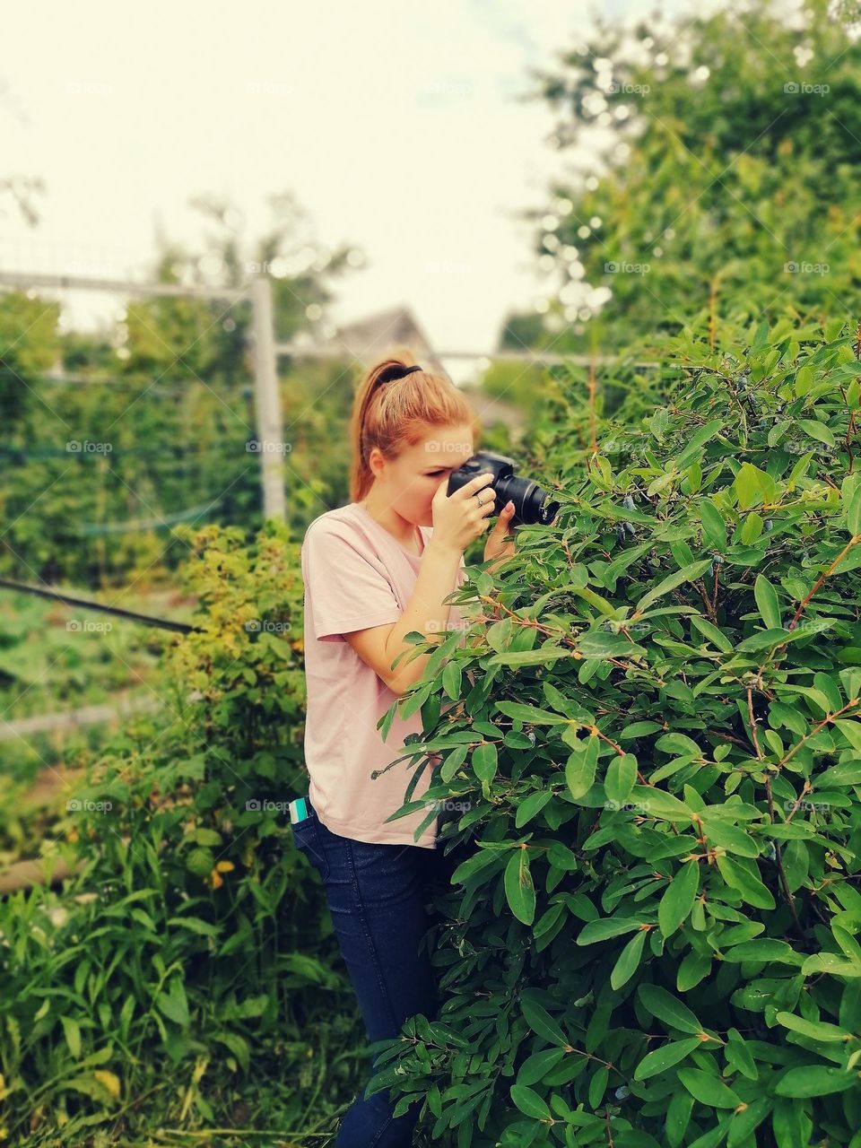 girl taking a picture of something in the bush