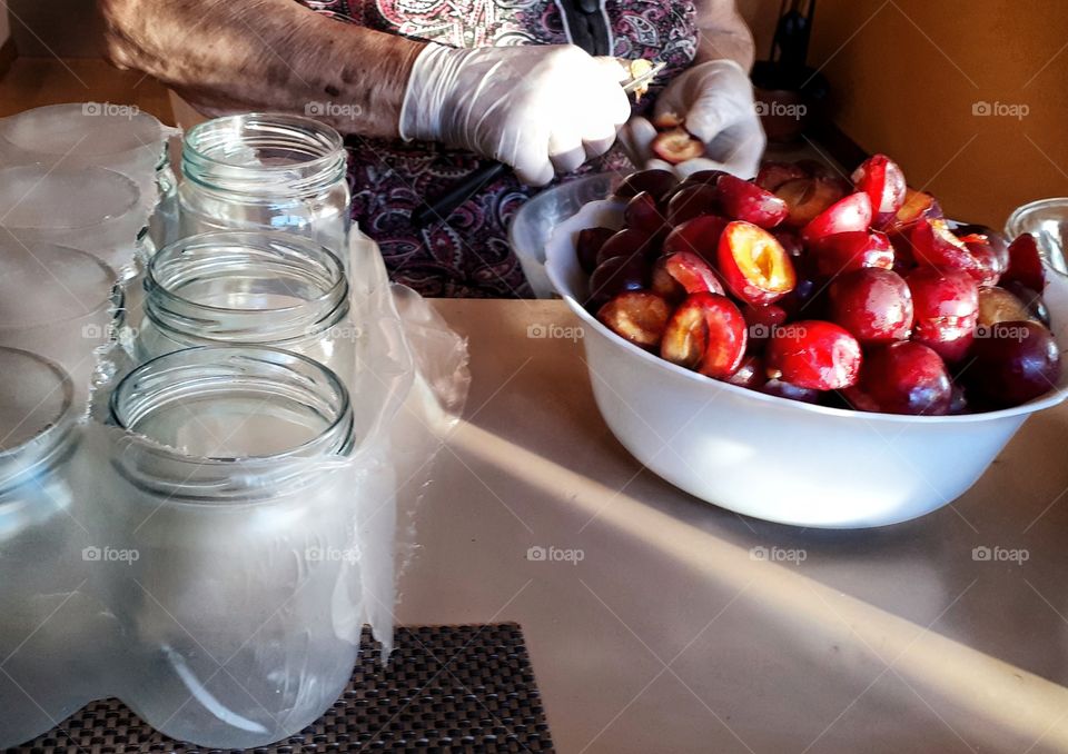Eastern europe loves compot,  sweet and fruity jarred summer. An elderly person depitting plums for compot.