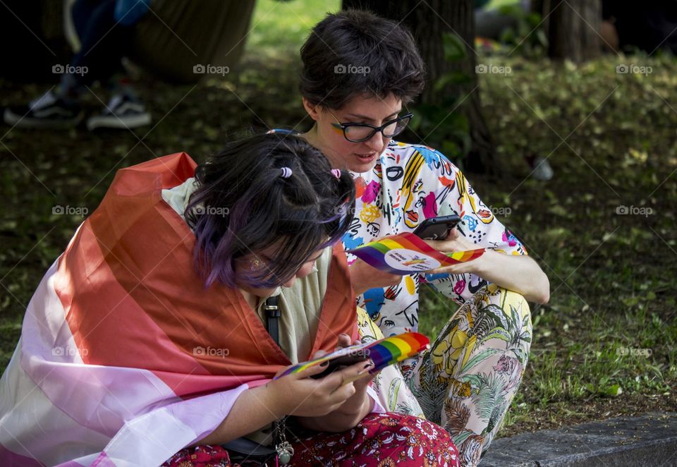 Teens sitting at the ground and holding phones