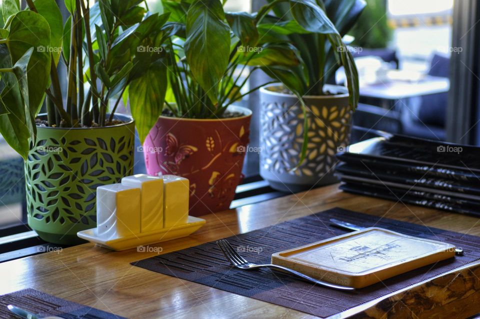 a table in a cafe decorated with potted flowers.