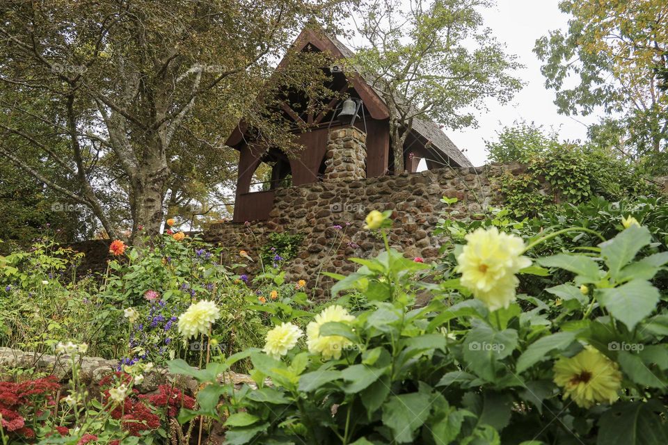 A small chapel is perched above a colorful flower garden.