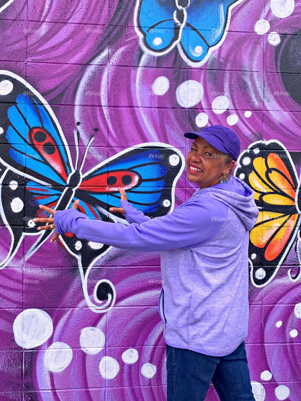 Color Purple - standing in front of the purple mural with her arms outstretched to become one with the art