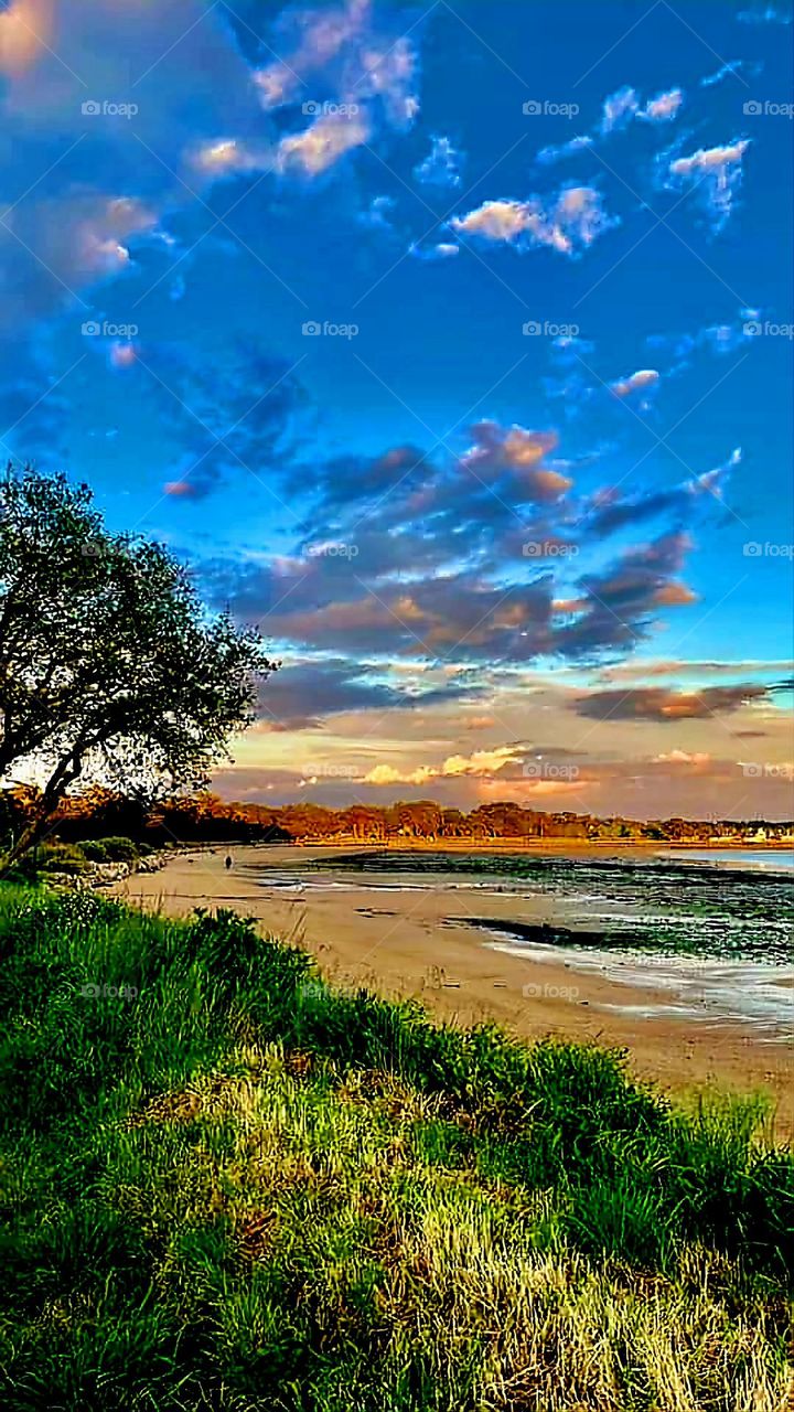 Sunrise's colour explosion under a cloudy bright blue sky and over Locmiquel's beach