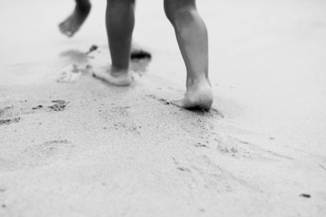 kids footprints in sand. kids playing on beach and leaving footprints on sand near water,monochrome photo