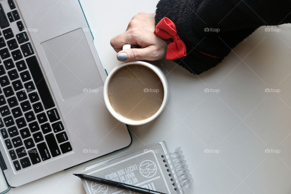 Working on computer holding a white coffee cup
