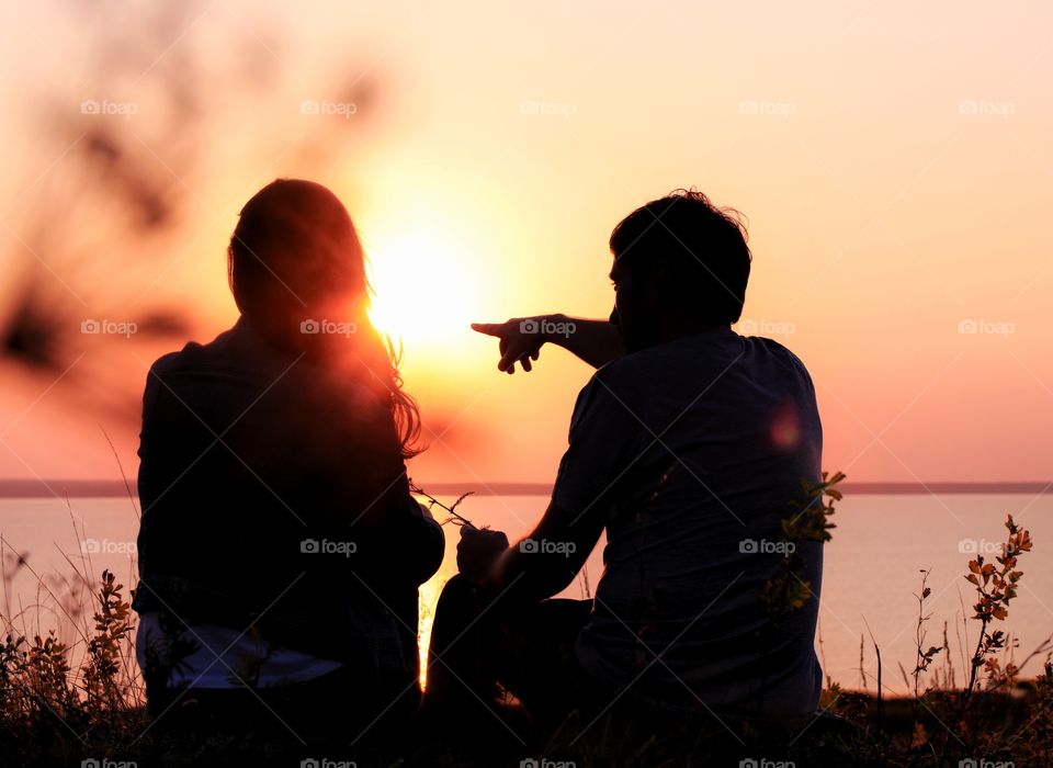 Silhouettes of man and woman at sunset on the lake