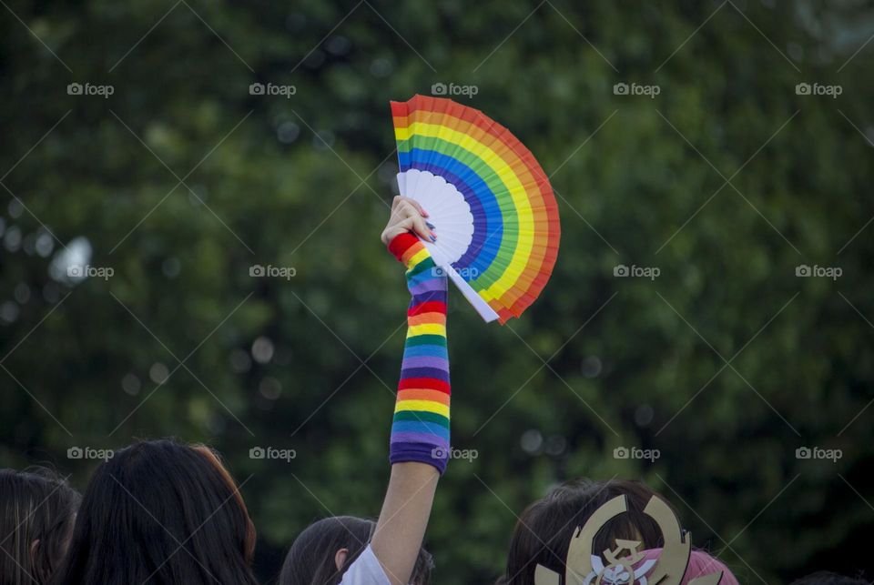 Rainbow colors fan in a hand over the crowd