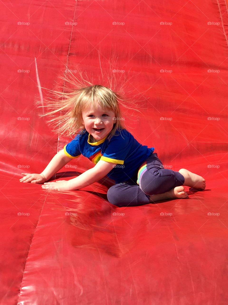 Young boy happily playing on a red inflatable slide in the spring sun. Lots of fun in north devon 