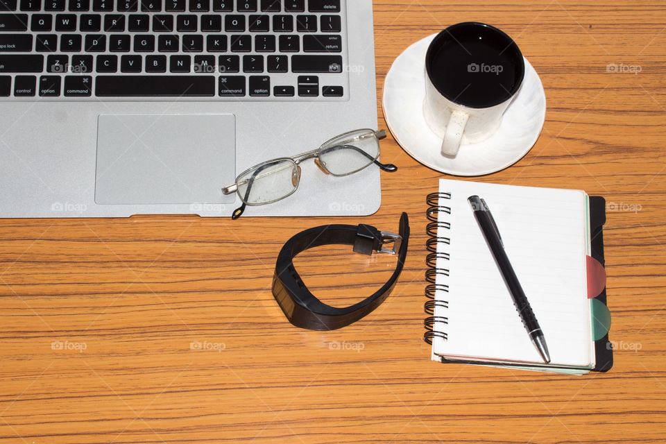 Desk with open notebook, wrist watch, eye glasses, pen and a cup of coffee. Top view with copy space. Business still life concept with office stuff on table. Education, working or planning concept