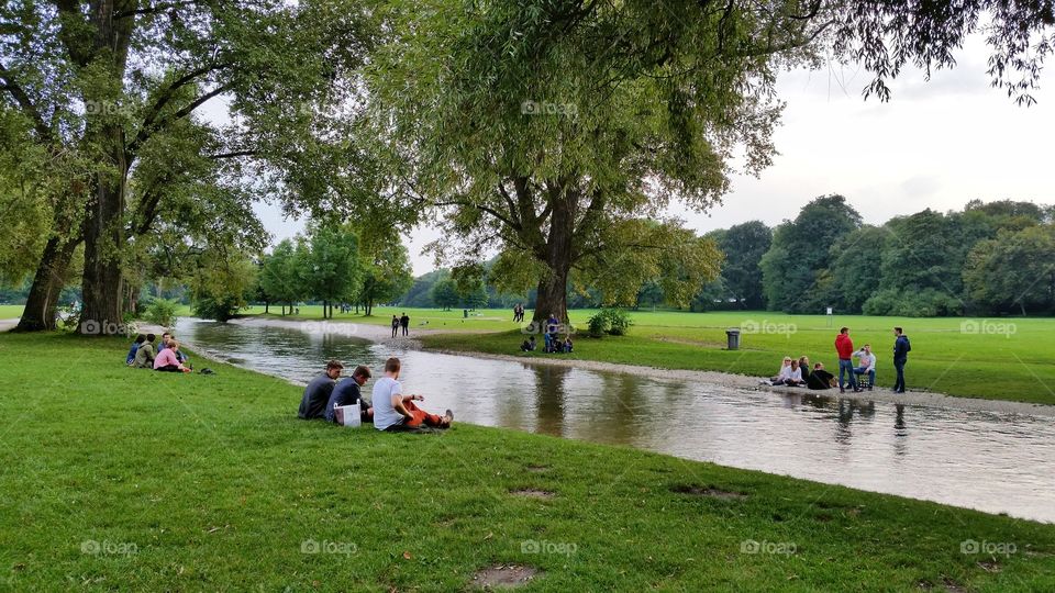 Friends are hanging out near the river in Englischergarten in Munich, Germany.