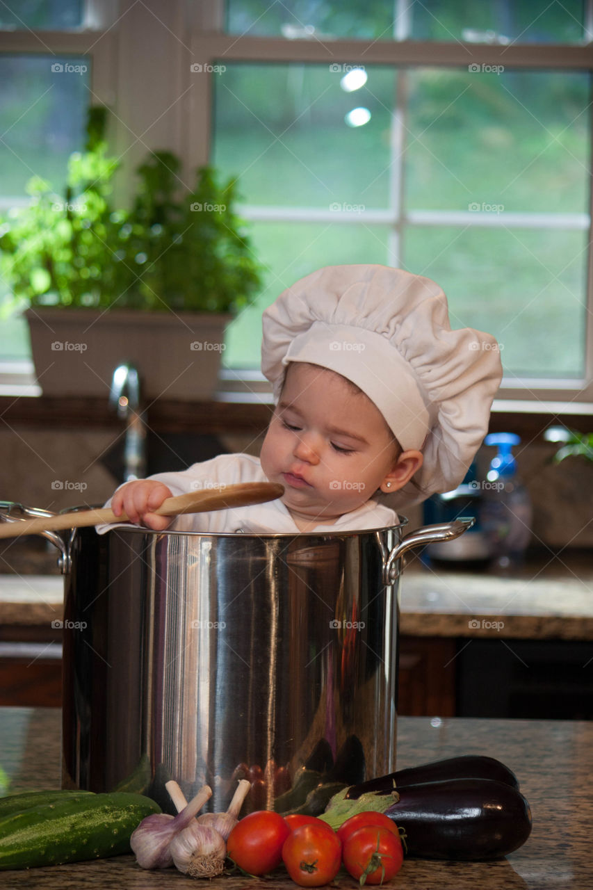 Cute baby chef inside cooking utensil