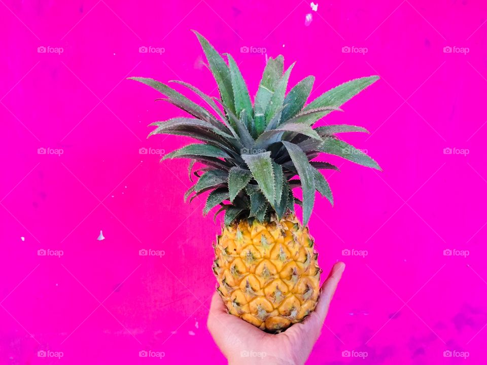 A yellow pineapple combination with a pink background