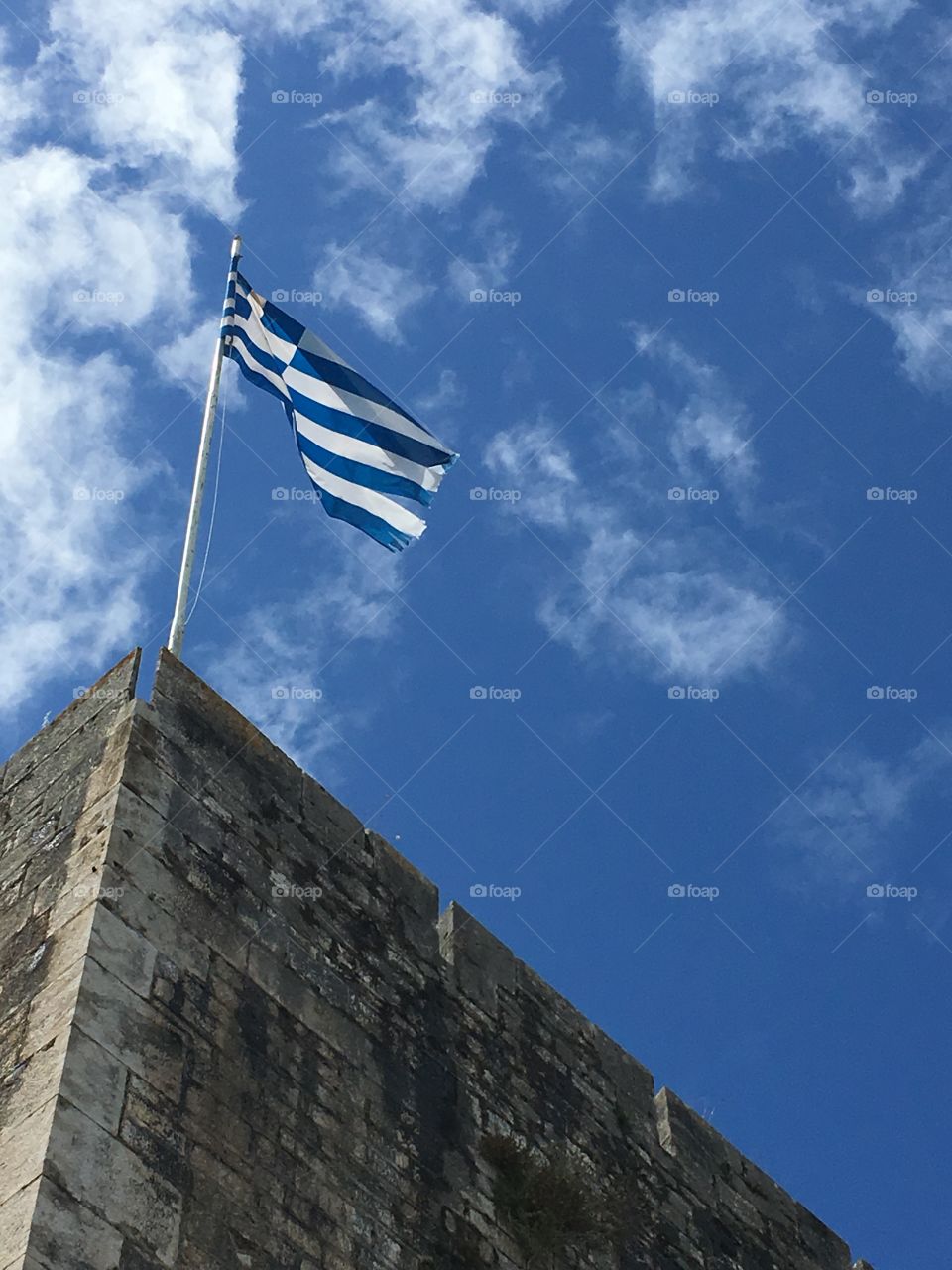 Greek flag flying in the wind on top of the New Fortress, Corfu Town, Greece