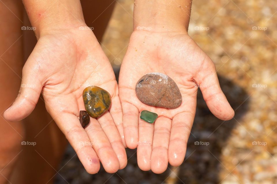 Stones in child hand on sea beach