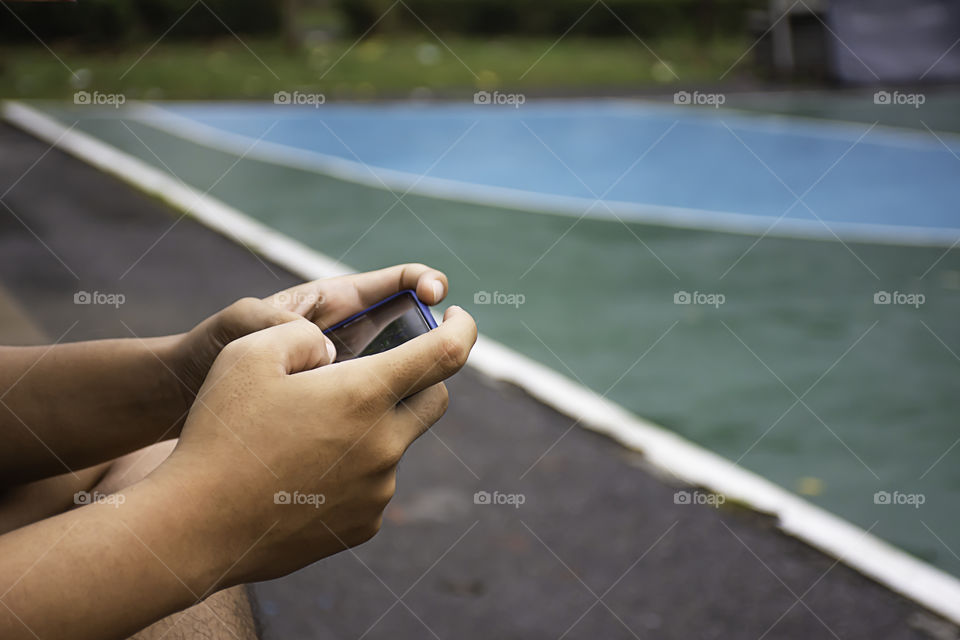 Hand holding telephone Background on basketball court.