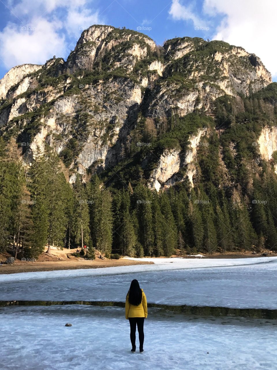 Woman standing in frozen lake, Italy - Lago di Braies