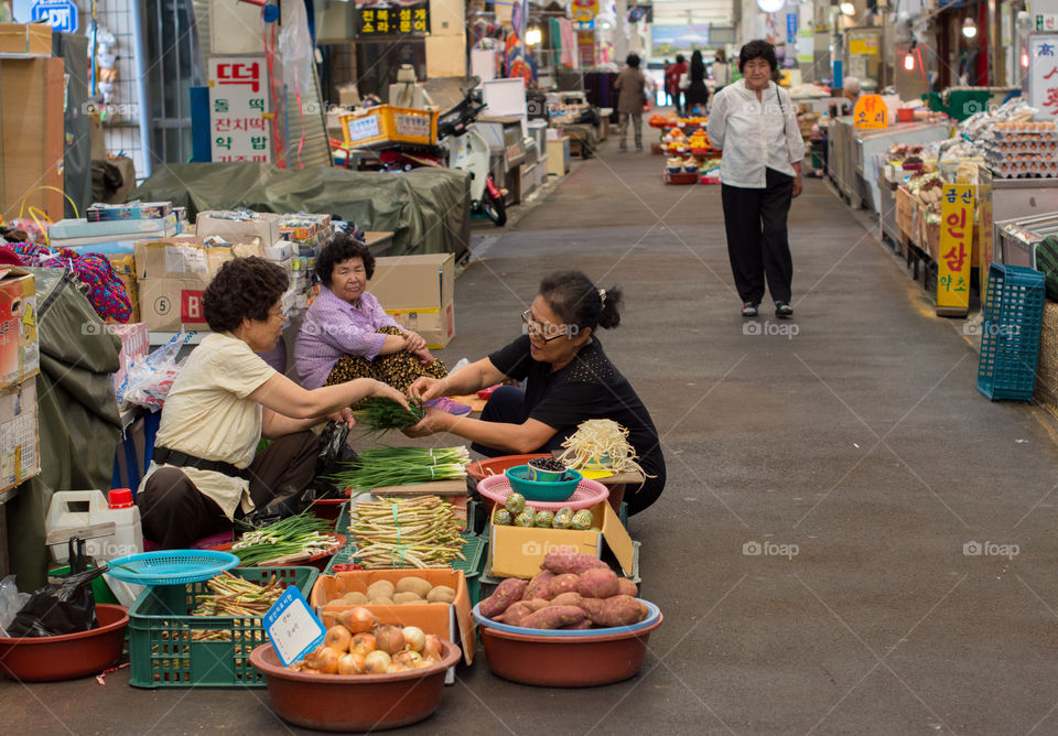 Woman selling vegetables to customer in Dongmun market, Jeju, South Korea.