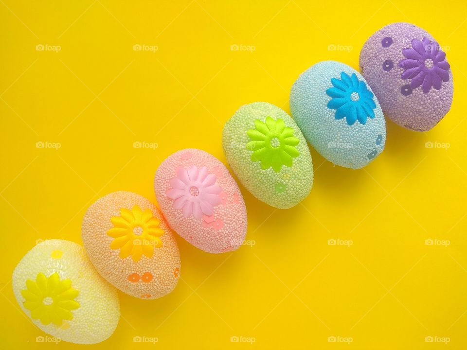 six colorful easter eggs on a yellow background