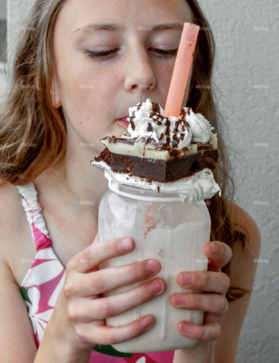 Yum - eating a decadent milkshake topped with a brownie delight 