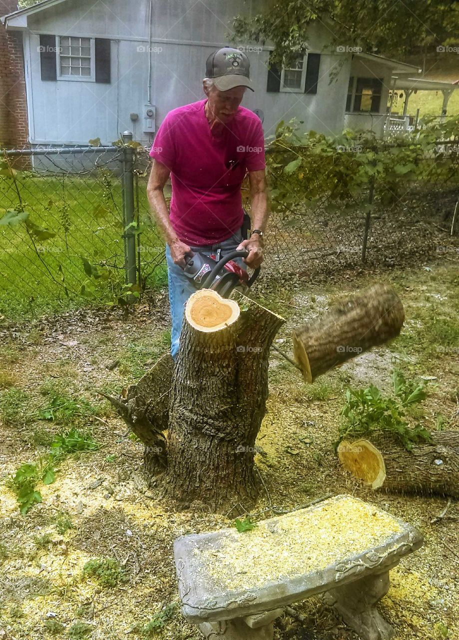 elderly man using chainsaw