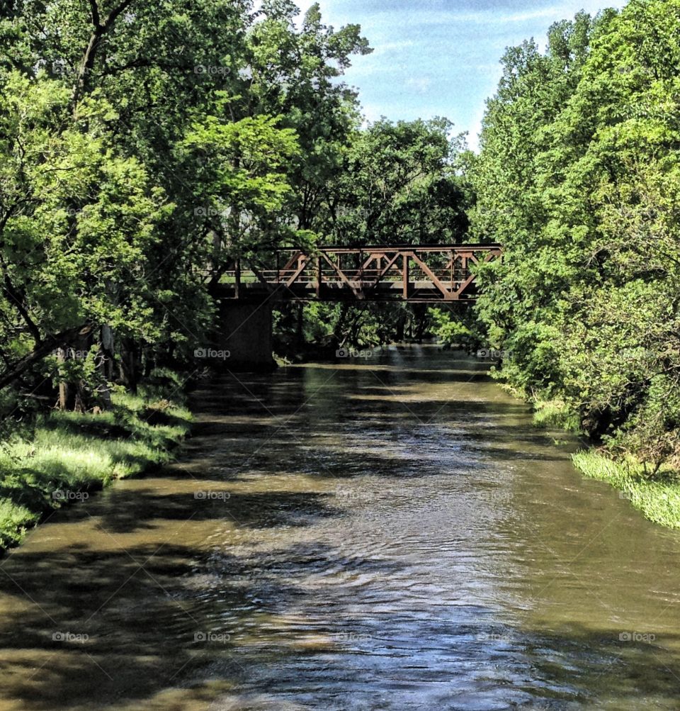 Looking upstream. An old pony truss bridge carries a road across the creek in the distance 