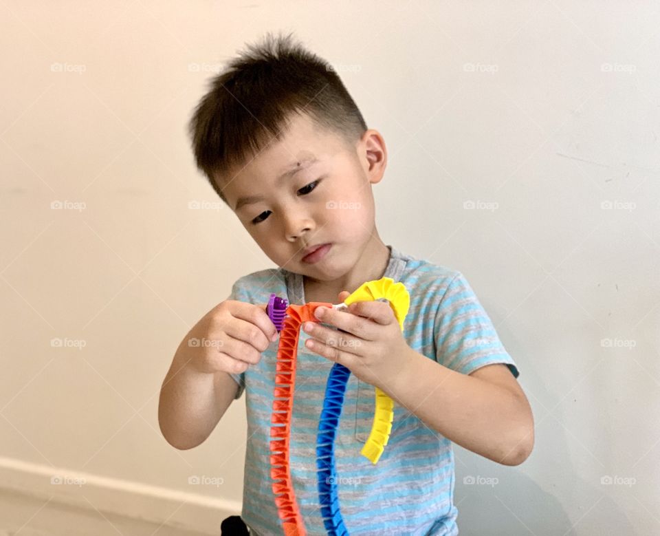 Asian boy playing with colourful toys 