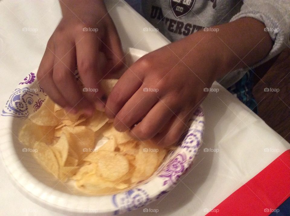 Child with hands in potato chips crisps. Child with hands in potato chips crisps