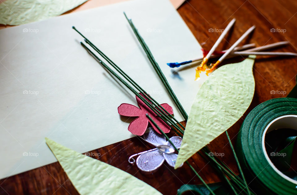 Paper arts supplies textured cut out paper flowers and leaves with green tape roll and wires and toothpicks to make art project 