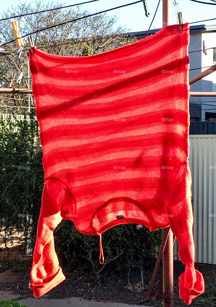 Red sweater hanging on clothesline outdoors