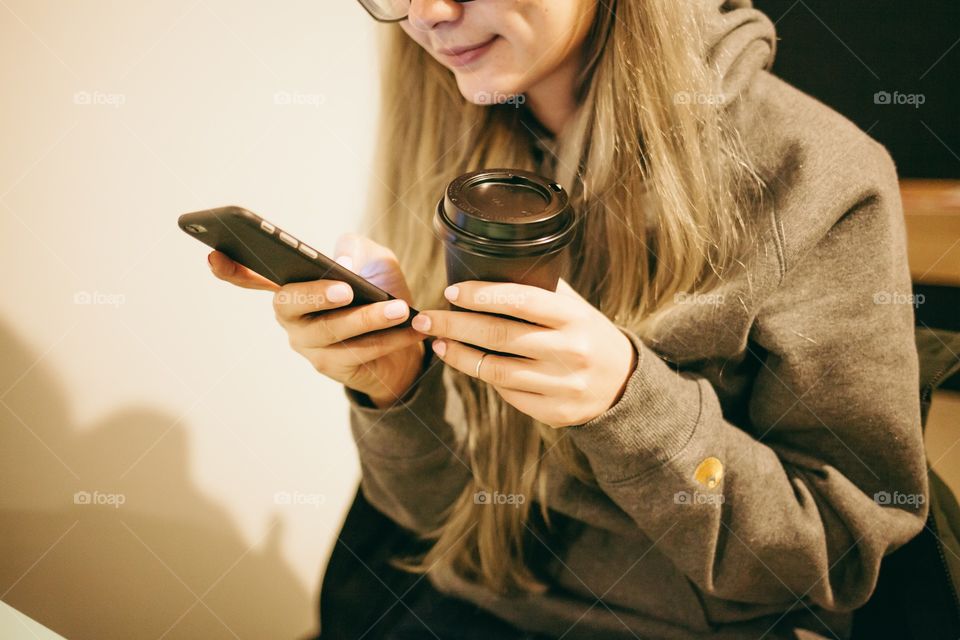 Girl using mobile and drinking coffee