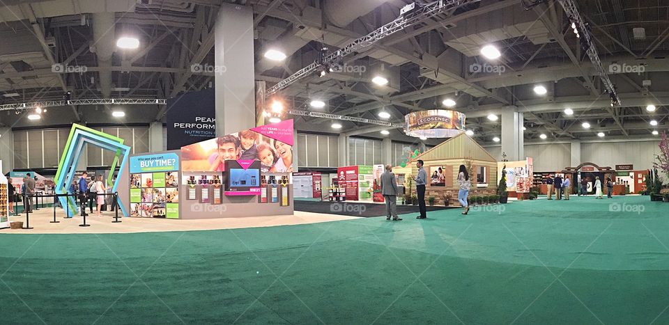 Convention center - a view of the product hall at a business convention.  A very expansive room filled with different displays and exhibits. 