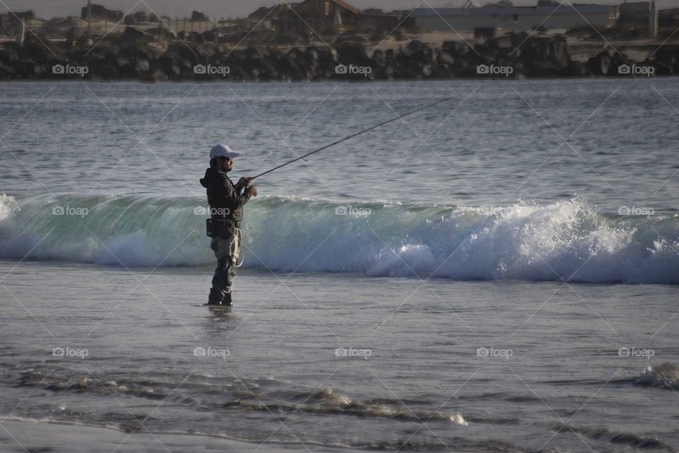 fisherman fishing at the shore of the beach