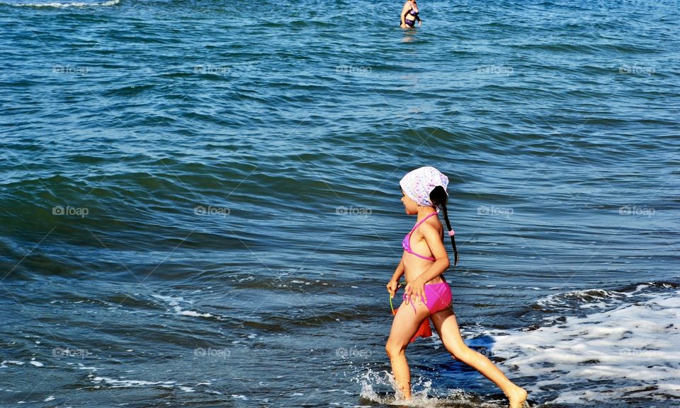 happy little girl in a swimsuit runs to the sea
