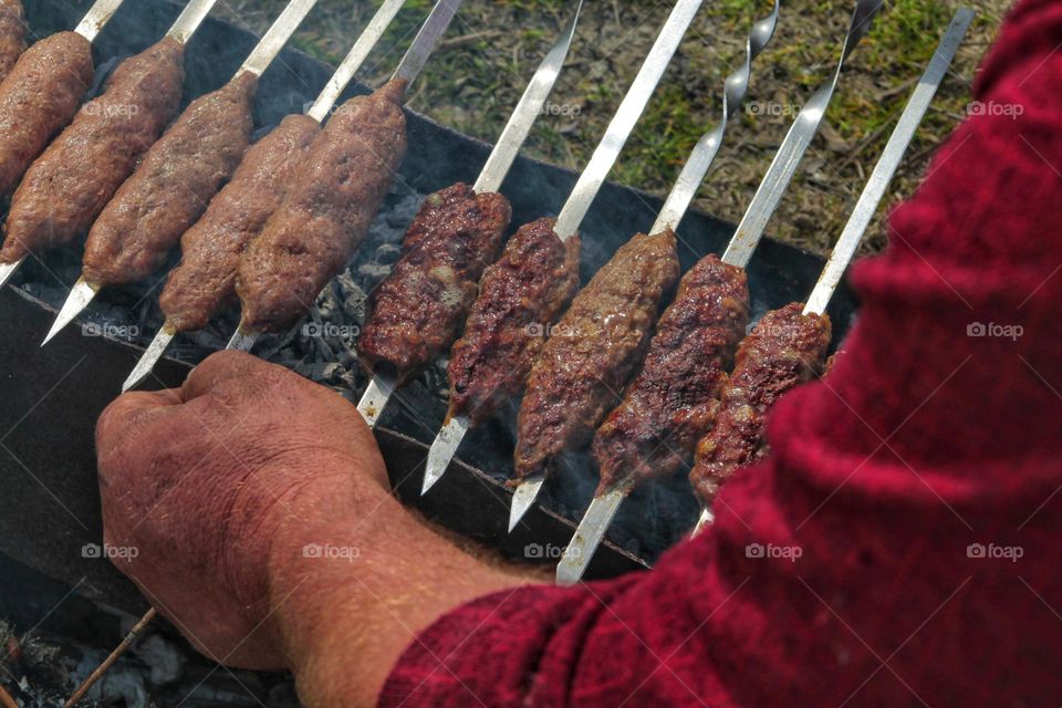 a man's hand flips a grilled meat dish