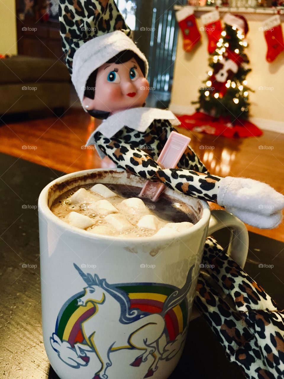 Naughty elf stirs hot cocoa with marshmallows 