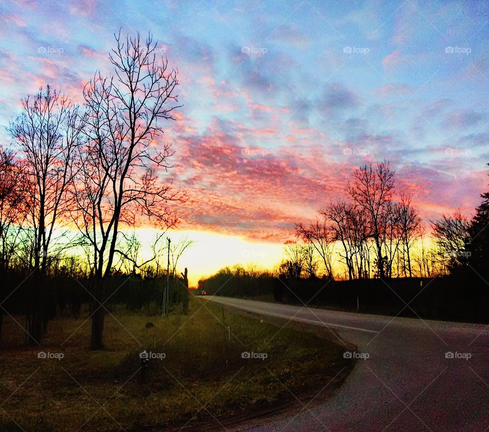 pink, yellow, and purple sky as the sunsets on a country road