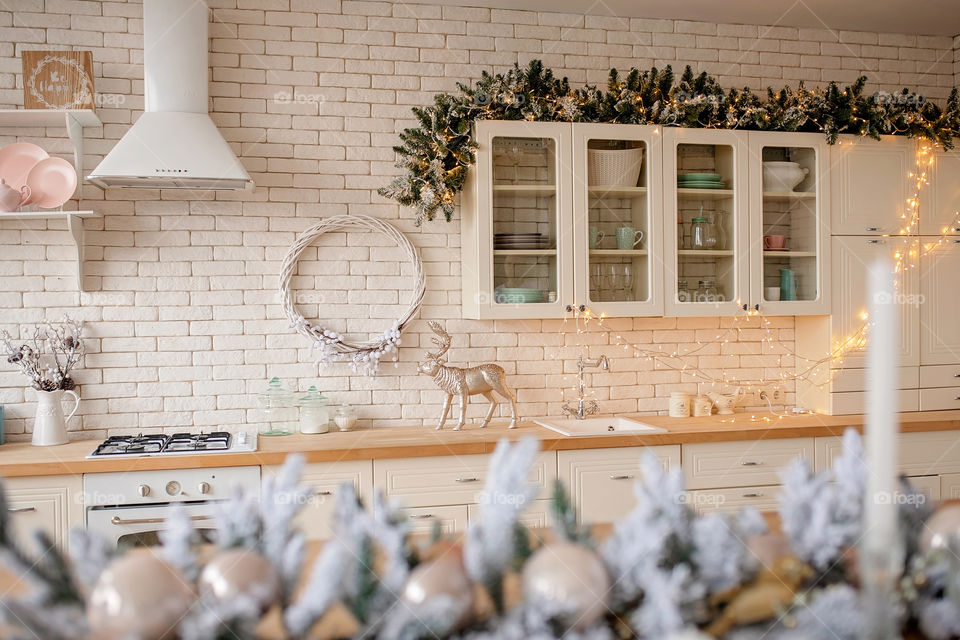 Festive winter cozy kitchen interior with garlands, decorations and gifts.  Christmas dinner at the decorated table.