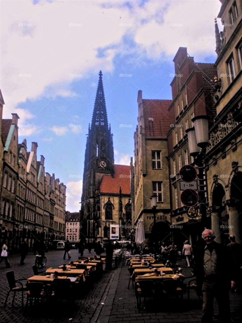 Man walking past an empty restaurant with church in the background