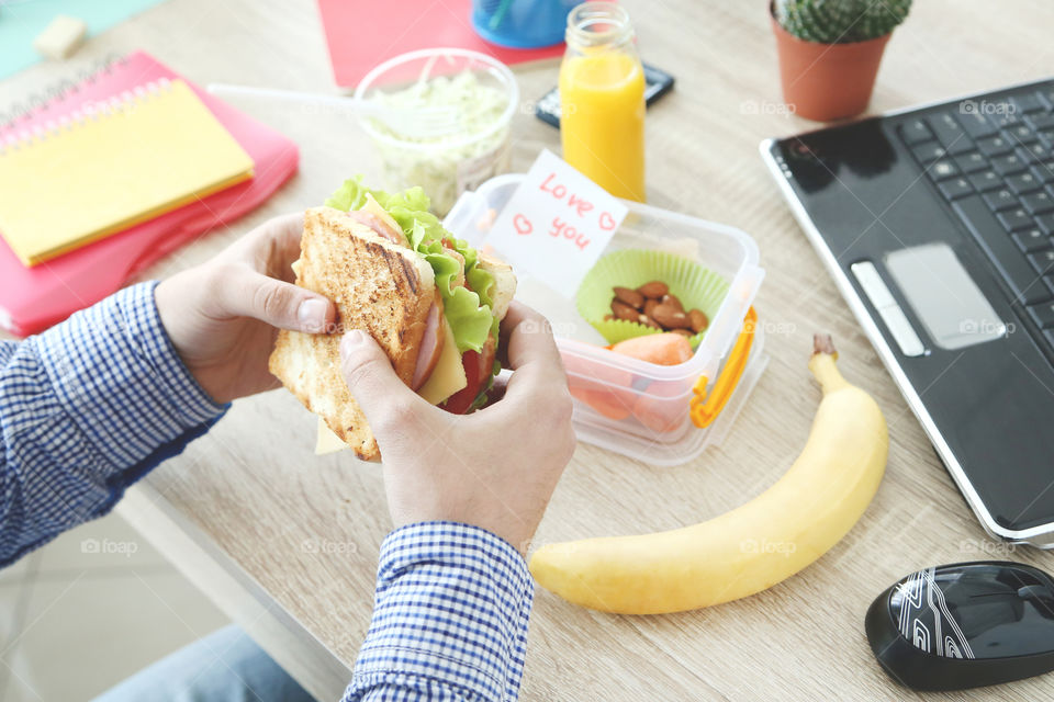 Man hands holding a tasty sandwich. Lunch at work, breakfast.